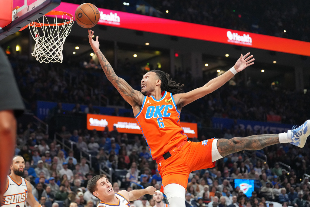 Oklahoma City Thunder forward Jaylin Williams, top, shoots over Phoenix Suns guard Collin Gillespie, center bottom, during the second half of an NBA Cup basketball game, Friday, Nov. 28, 2025, in Oklahoma City. (AP Photo/Kyle Phillips)
