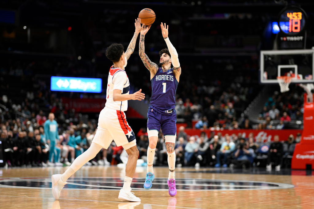 Charlotte Hornets guard LaMelo Ball (1) shoots against Washington Wizards guard Will Riley, left, during the first half of an NBA basketball game, Sunday, Feb. 22, 2026, in Washington. (AP Photo/Nick Wass)
