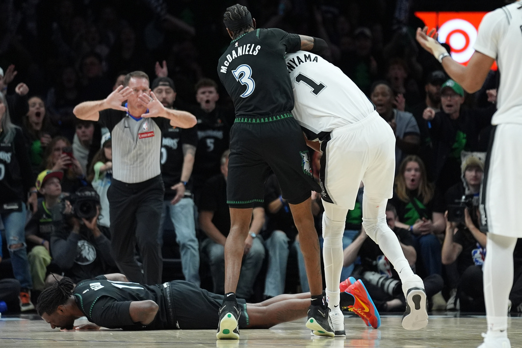 Minnesota Timberwolves center Naz Reid (11) falls to the court after he was fouled by San Antonio Spurs forward Victor Wembanyama (1) as he and forward Jaden McDaniels (3) battled for a rebound during the first half of Game 4 of an NBA basketball second-round playoffs series in Minneapolis, Sunday, May 10, 2026. (AP Photo/Abbie Parr)