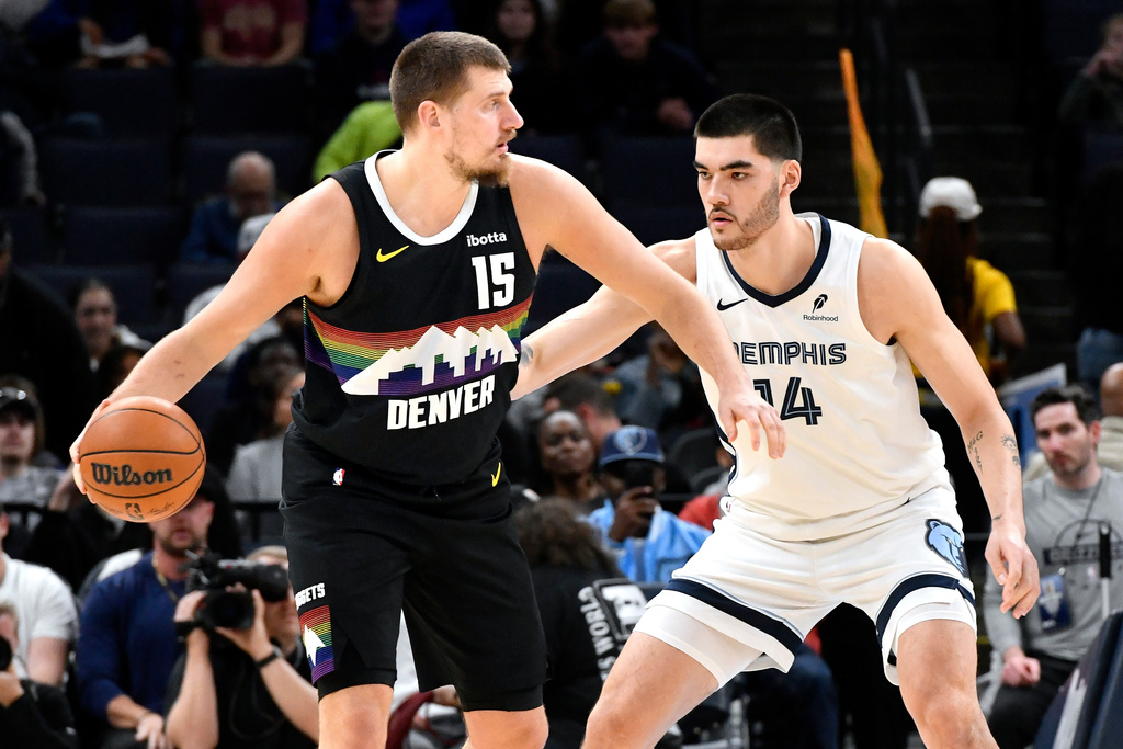 Denver Nuggets center Nikola Jokic (15) handles the ball against Memphis Grizzlies center Zach Edey in the first half of an NBA basketball game, Monday, Nov. 24, 2025, in Memphis, Tenn. (AP Photo/Brandon Dill)