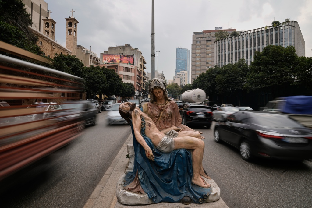 Cars speed past a roadside statue depicting the Virgin Mary holding the body of Jesus, in Beirut, Lebanon, Thursday, Nov. 13, 2025. (AP Photo/Hassan Ammar)