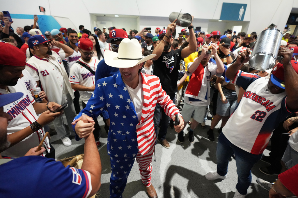 A USA fan shakes hands with a Dominican Republic fan before a World Baseball Classic semifinal game between the teams, Sunday, March 15, 2026, in Miami. (AP Photo/Rebecca Blackwell)