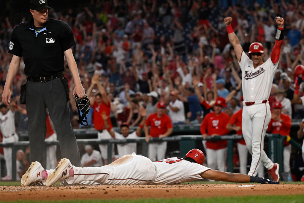 Washington Nationals' Drew Millas, right, celebrates as the Nationals' James Wood slides into home on a inside the park grand slam home run during the second inning of a baseball game against the New York Mets, Tuesday, May 19, 2026, in Washington. (AP Photo/John McDonnell)