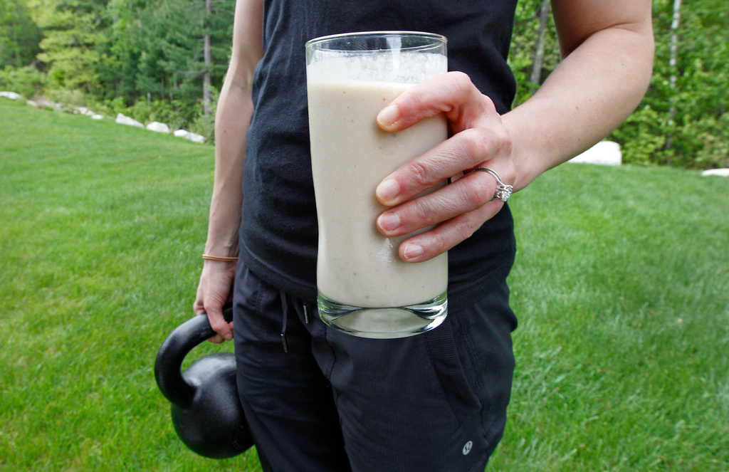 FILE - A woman holds a protein shake and a kettlebell as she poses at her home in Tyngsborough, Mass., on May 15, 2012. (AP Photo/Charles Krupa, File)