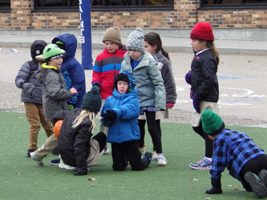 Children wearing coats, hats and gloves play with a ball Friday, Nov. 7, 2025, at St. Mary's Elementary School in Bismarck, N.D. (AP Photo/Jack Dura)