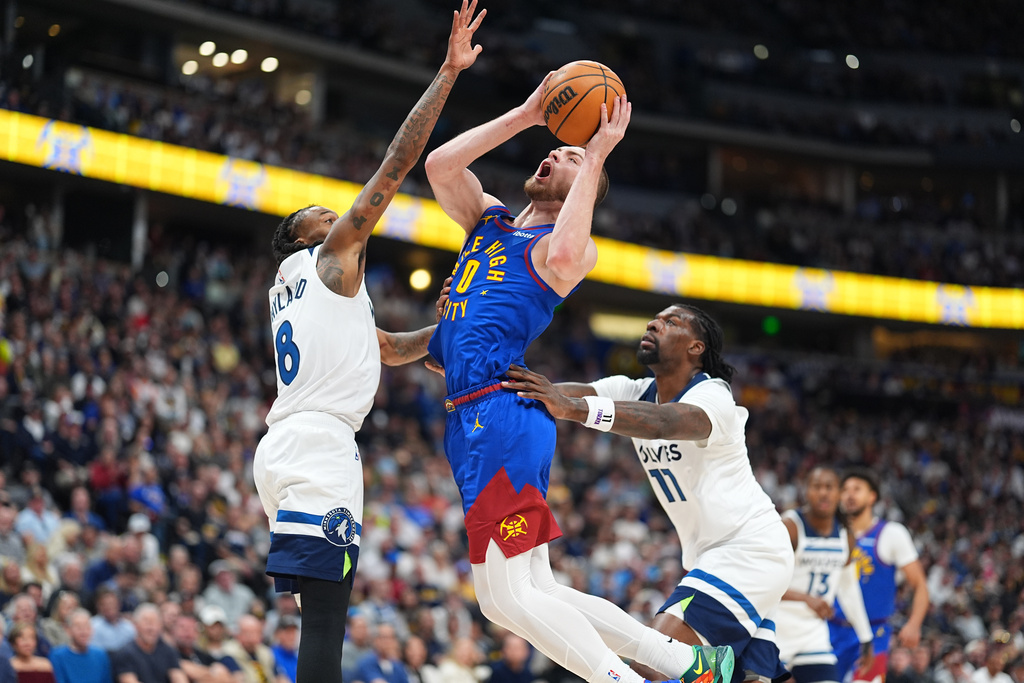 Denver Nuggets guard Christian Braun, center, drives to the basket between Minnesota Timberwolves guard Bones Hyland, left, and center Naz Reid (11) in the first half of an NBA basketball game Sunday, March 1, 2026, in Denver. (AP Photo/David Zalubowski)
