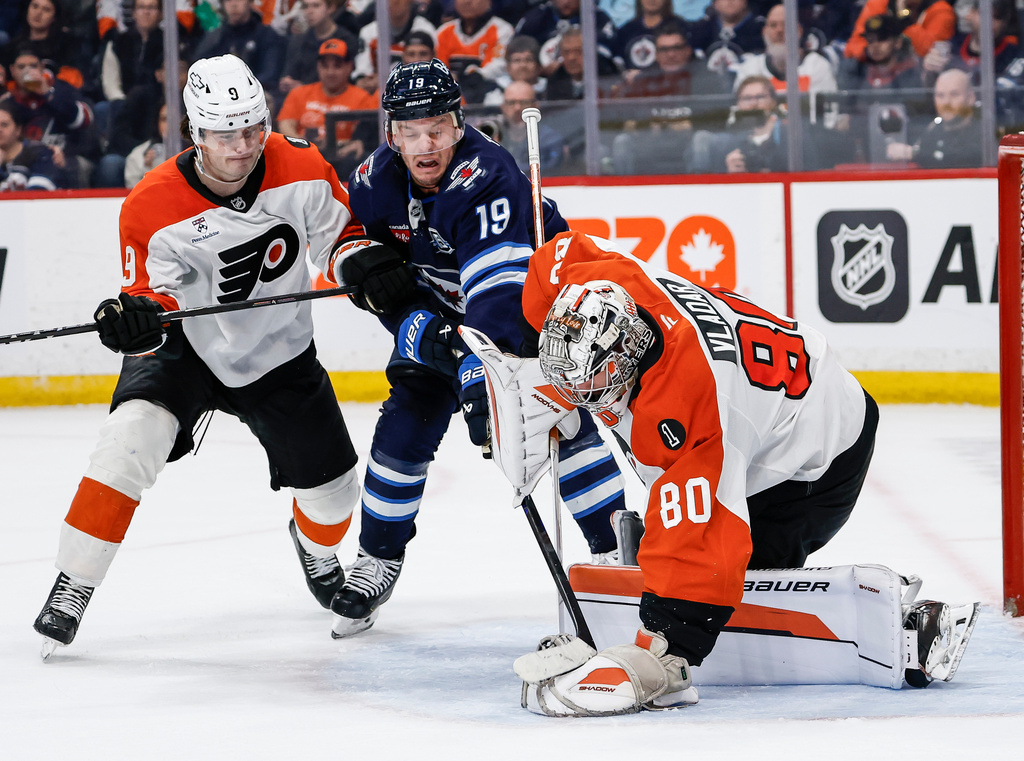 Winnipeg Jets' Jonathan Toews (19) digs for the rebound as Philadelphia Flyers goaltender Dan Vladar (80) saves the shot and Jamie Drysdale (9) defends during second period NHL action in Winnipeg, Saturday, April 11, 2026. (John Woods/The Canadian Press via AP)