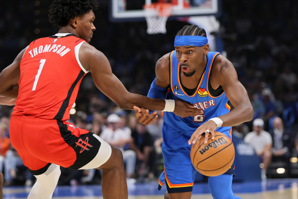 Oklahoma City Thunder guard Shai Gilgeous-Alexander, right, drives against Houston Rockets guard Amen Thompson (1) during the first half of an NBA basketball game Tuesday, Oct. 21, 2025, in Oklahoma City. (AP Photo/Nate Billings)