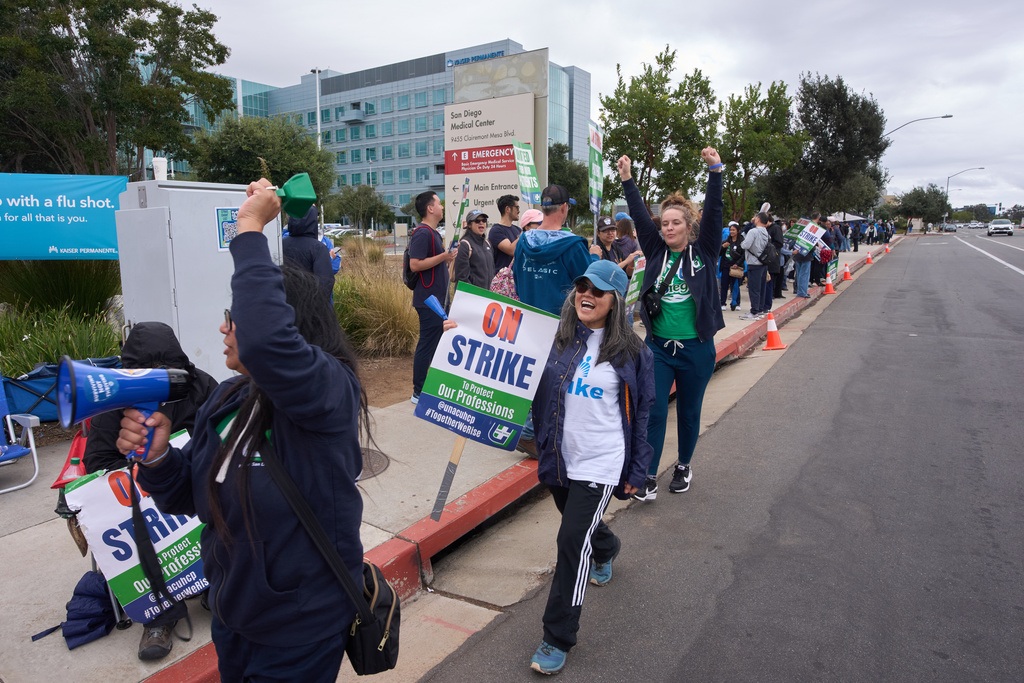 Kaiser Permanente health care workers hold signs and chant slogans while on strike in front of the Kaiser Permanente San Diego Medical Center Tuesday, Oct. 14, 2025, in San Diego. (AP Photo/Gregory Bull)