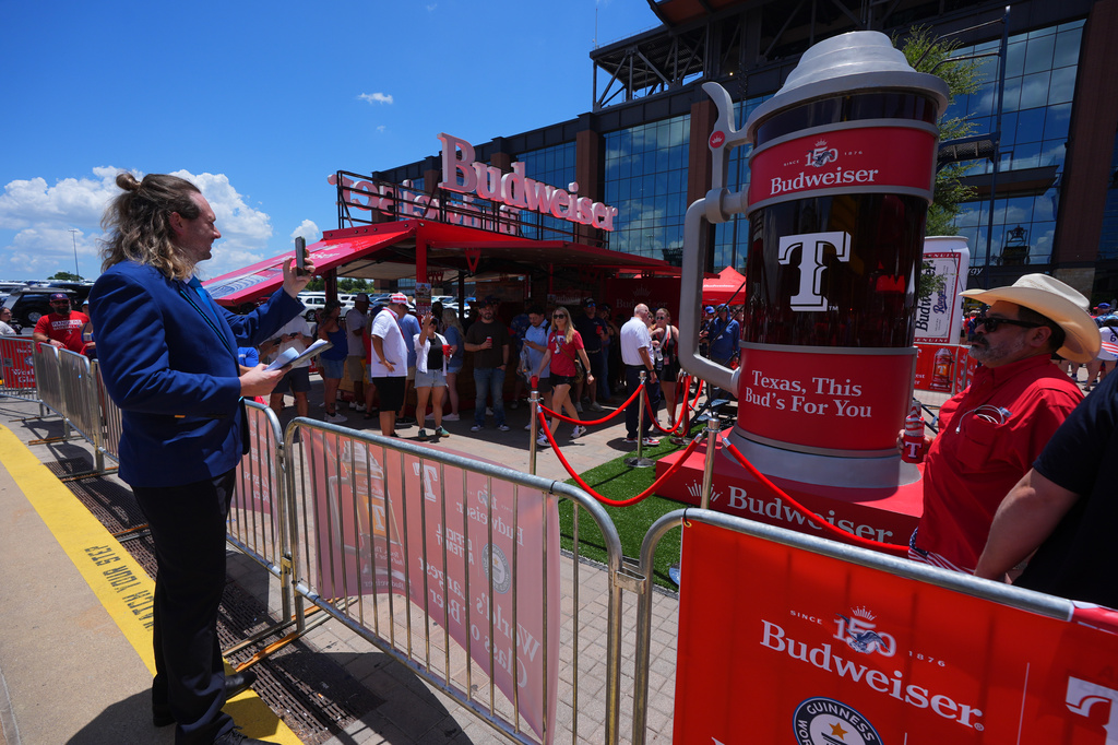 Guinness World Records adjudicator Thomas Bradford, left, makes a photo before certifying a world record for Largest Glass of Beer ahead of a baseball game between the Detroit Tigers and Texas Rangers, Saturday, July 4, 2026, in Arlington, Texas. (AP Photo/LM Otero)