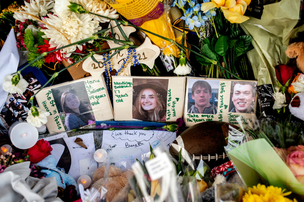 FILE - Photographs of four students &mdash; Hana St. Juliana, 14; Madisyn Baldwin, 17; Tate Myre, 16; and Justin Shilling, 17 &mdash; sit among bouquets of flowers, teddy bears and other personal items left at the memorial site for victims of the school shooting, outside Oxford High School, Dec. 7, 2021, in Oxford, Mich. (Jake May/The Flint Journal via AP, File)