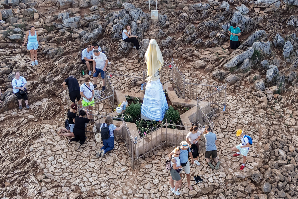 An aerial view of pilgrims praying next to the vandalized statue of the Virgin Mary, which has been covered with a white sheet, on Apparition Hill in Medjugorje, Bosnia, Tuesday, July 28, 2026. (AP Photo)