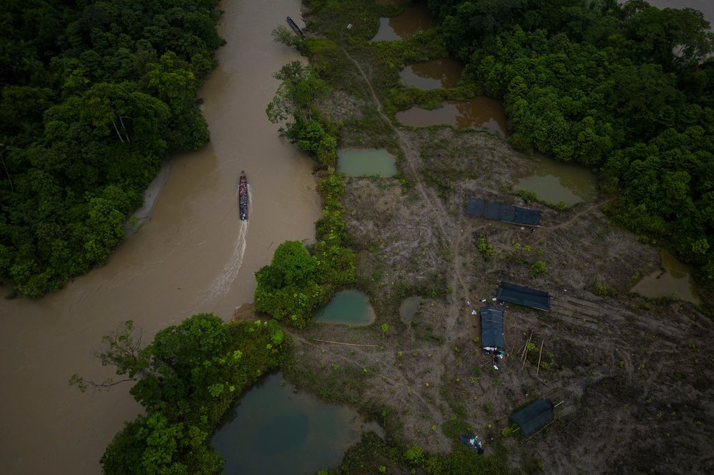 FILE - A boat, with gasoline to be taken to illegal mining machinery, maneuvers past an area that was mined near Paimado, Colombia, Sept. 24, 2024. (AP Photo/Ivan Valencia, File)