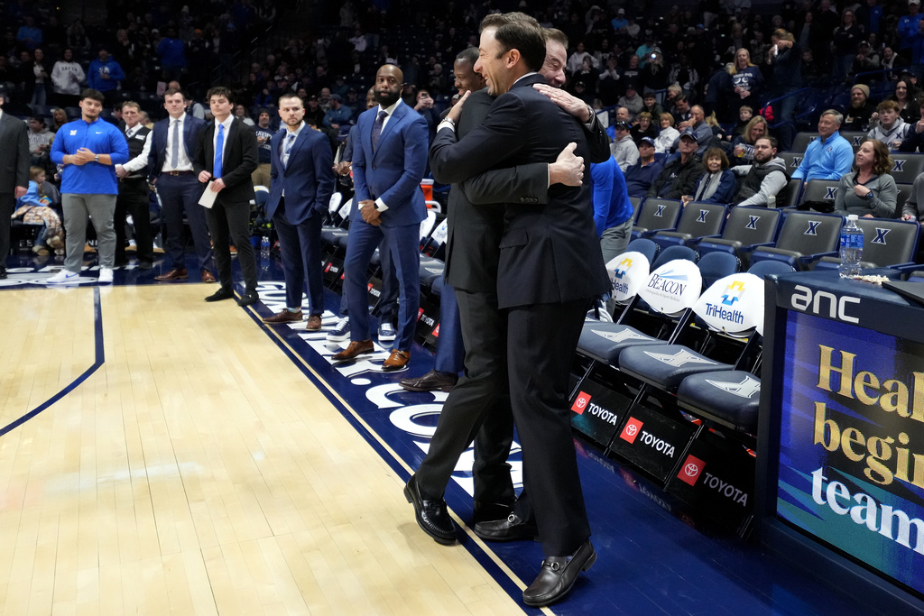 Xavier head coach Richard Pitino, right. wearing a full suit like his father, Rick Pitino, left, embraces him before a college basketball game St. John's, Saturday, Jan. 24, 2026, in Cincinnati. (AP Photo/Kareem Elgazzar)
