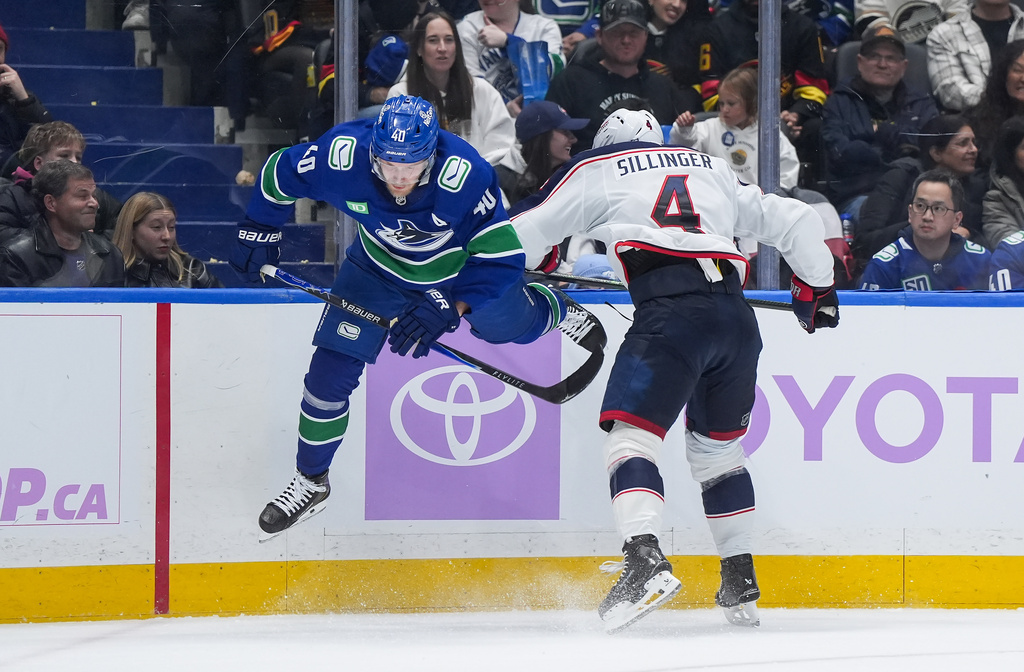 Columbus Blue Jackets' Cole Sillinger (4) checks Vancouver Canucks' Elias Pettersson (40) during the second period of an NHL hockey game in Vancouver, on Saturday, Nov. 8, 2025. (Darryl Dyck/The Canadian Press via AP)