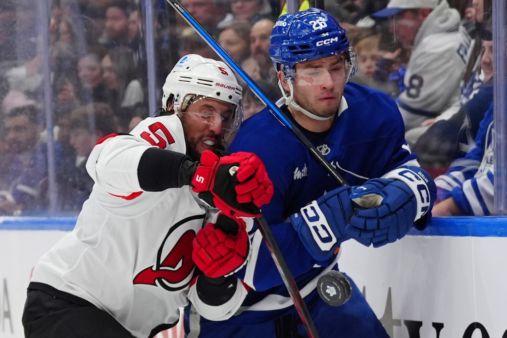 Toronto Maple Leafs' Jacob Quillan and New Jersey Devils defenceman Brenden Dillon (5) battle along the boards for the puck during the second period of an NHL hockey game in Toronto, Tuesday Dec. 30, 2025. (Frank Gunn/The Canadian Press via AP)