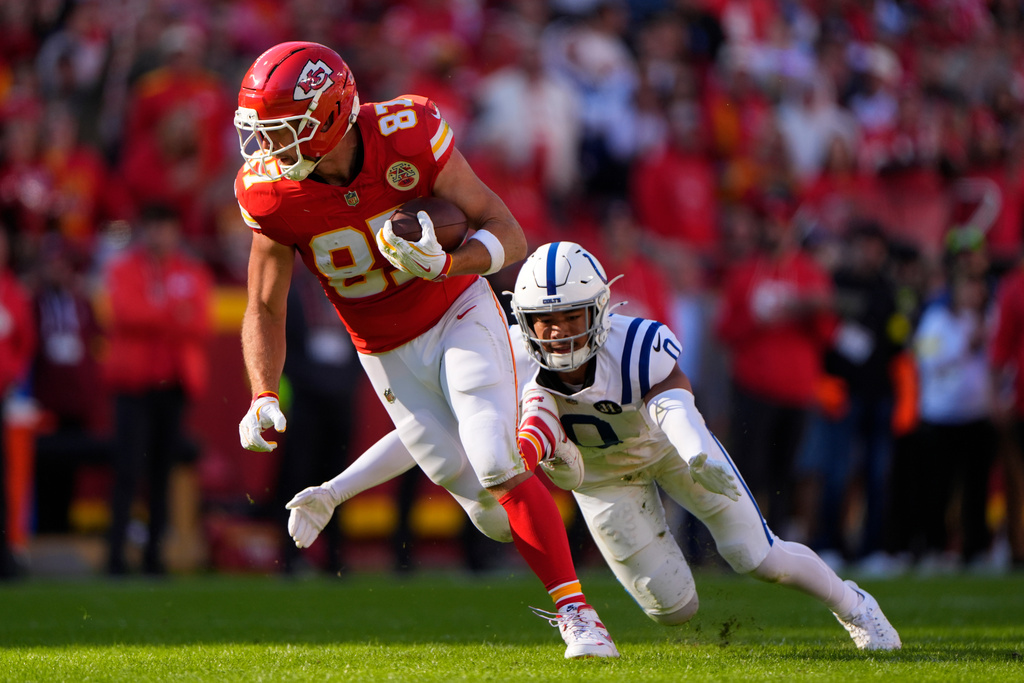 Kansas City Chiefs tight end Travis Kelce (87) runs after a catch in front of Indianapolis Colts safety Camryn Bynum (0) during the first half of an NFL football game Sunday, Nov. 23, 2025, in Kansas City, Mo. (AP Photo/Charlie Riedel)