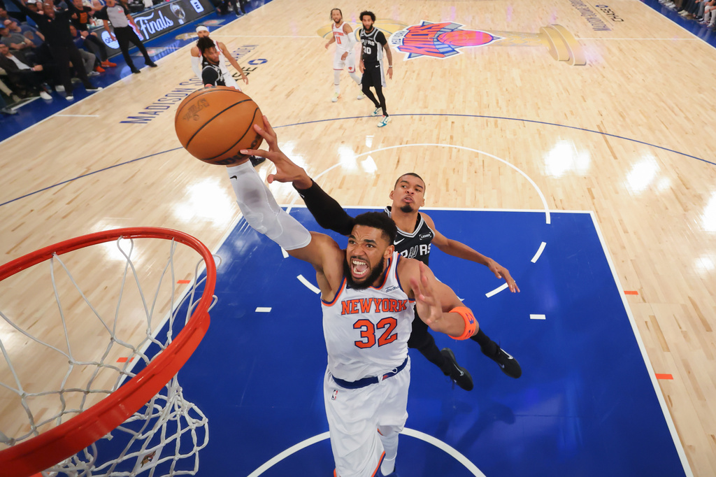 New York Knicks center Karl-Anthony Towns (32) dunks past San Antonio Spurs forward Victor Wembanyama during the first half of Game 4 of the NBA Finals basketball series, Monday, June 8, 2026, in New York. (Al Bello/Pool Photo via AP)