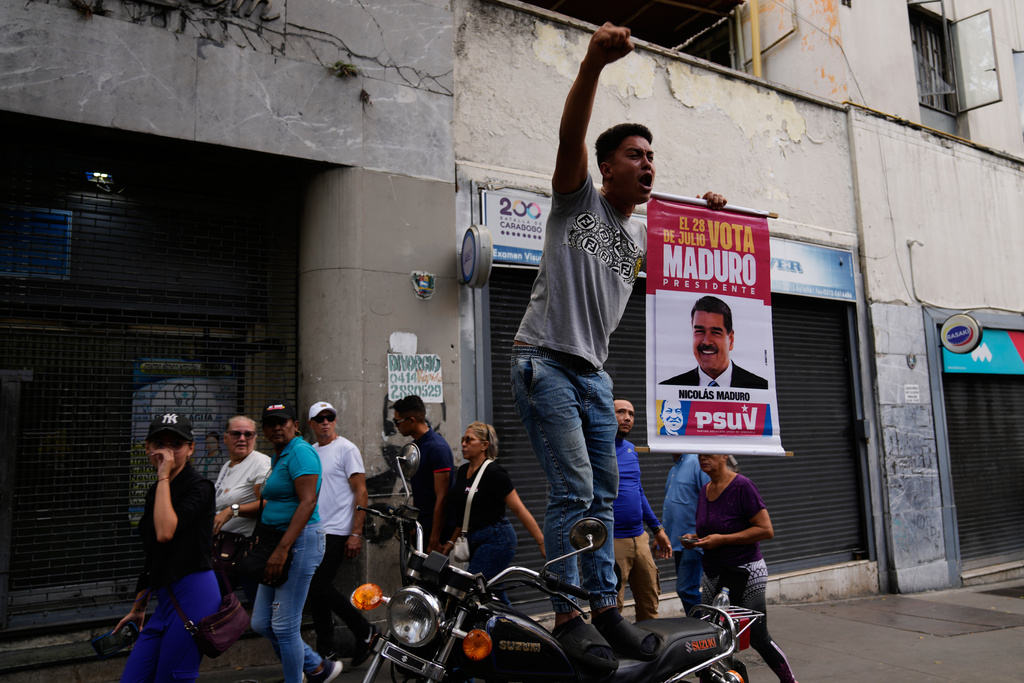 A government supporter holds a banner for President Nicolas Maduro during a protest demanding his release, after U.S. forces captured and flew him to the United States, in Caracas, Venezuela, Sunday, Jan. 4, 2026. (AP Photo/Ariana Cubillos)