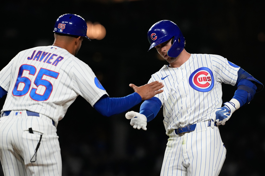 Chicago Cubs' Nico Hoerner, right, celebrates with first base coach Jose Javier, left, after hitting a one-run single during the eighth inning of a baseball game against the Milwaukee Brewers in Chicago, Tuesday, May 19, 2026. (AP Photo/Nam Y. Huh)