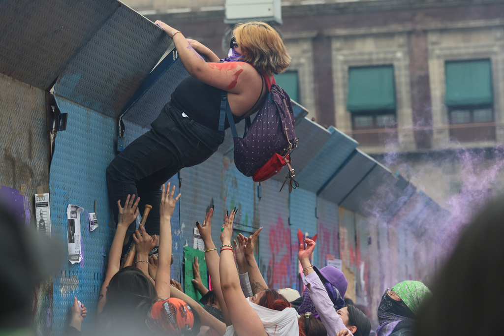 A protester climbs a barrier during a rally marking International Women's Day, at the Zocalo in Mexico City, Sunday, March 8, 2026. (AP Photo/Ginnette Riquelme)