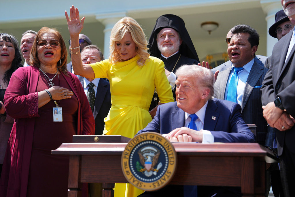 FILE - President Donald Trump sits at a desk as he and religious leaders listen to a musical performance before Trump signs an executive order during a National Day of Prayer event in the Rose Garden of the White House, May 1, 2025, in Washington. (AP Photo/Evan Vucci, File)