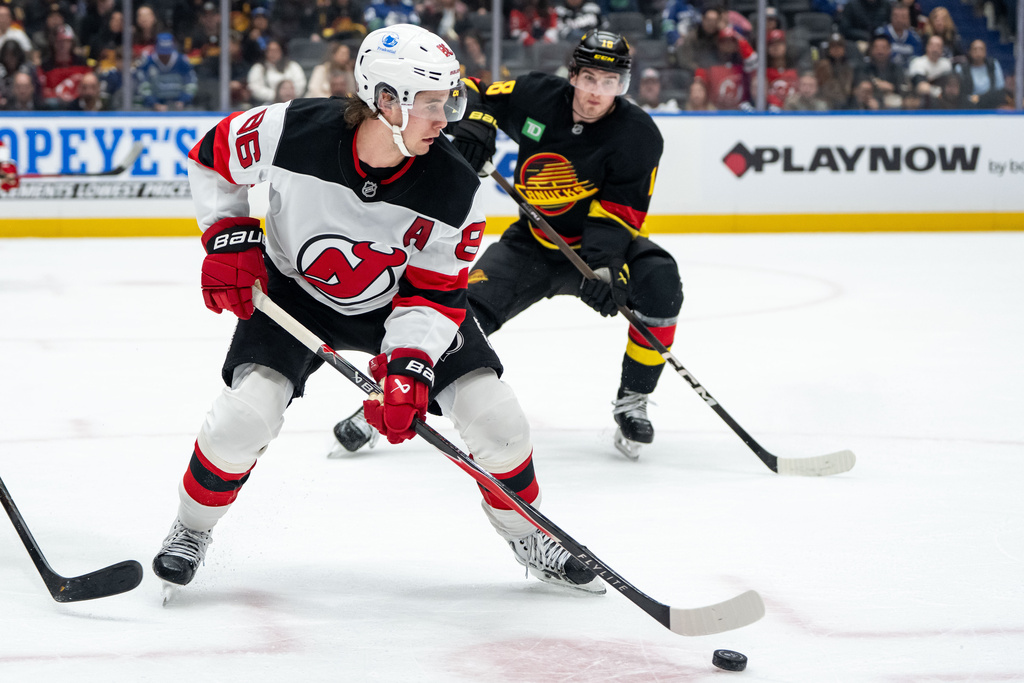 New Jersey Devils' Jack Hughes (86) skates with the puck as Vancouver Canucks' Drew O'Connor (18) watches during the second period of an NHL hockey game in Vancouver, British Columbia, Friday, Jan. 23, 2026. (Ethan Cairns/The Canadian Press via AP)
