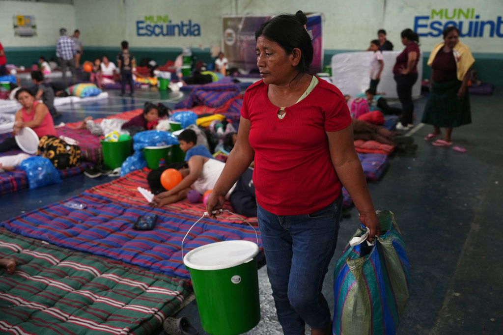 A woman evacuated from El Porvenir, a village on the slopes of the Fuego volcano, carries first aid supplies she was given after arriving at a temporary shelter in Escuintla, Guatemala, Tuesday, Aug. 4, 2026. (AP Photo/Moises Castillo)