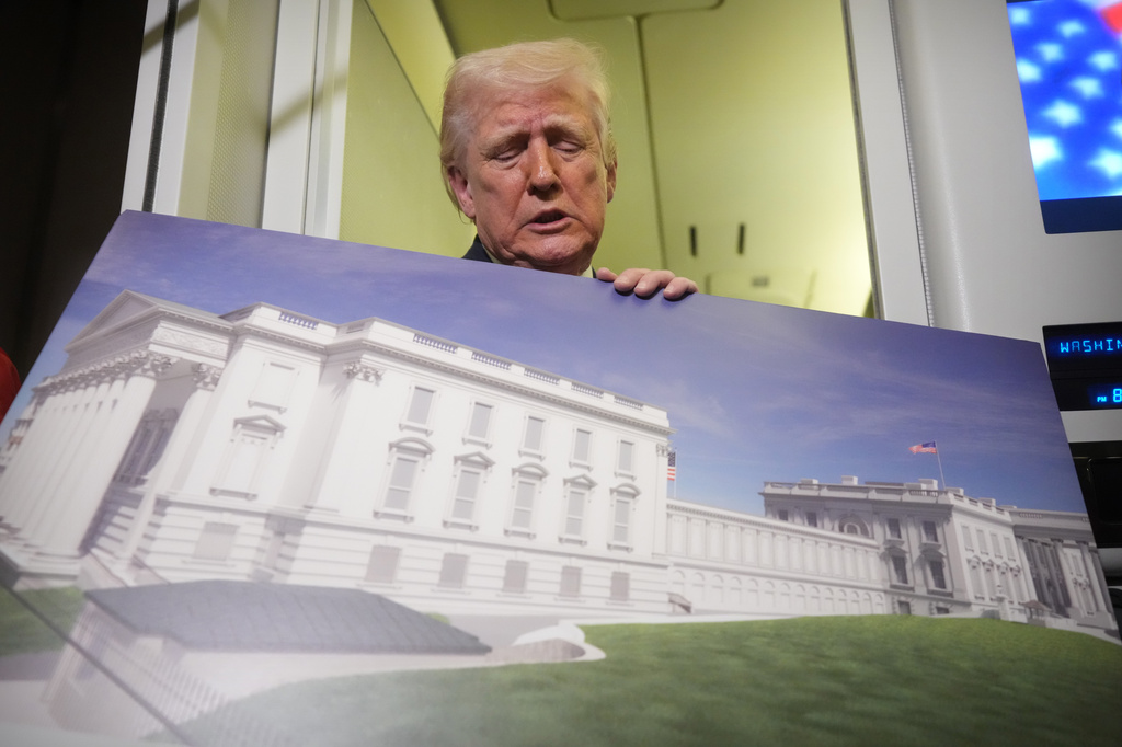 President Donald Trump holds a rendering of the proposed new East Wing of the White House as he speaks to reporters aboard Air Force One en route from West Palm Beach, Fla., to Joint Base Andrews, Md., Sunday, March 29, 2026. (AP Photo/Mark Schiefelbein)