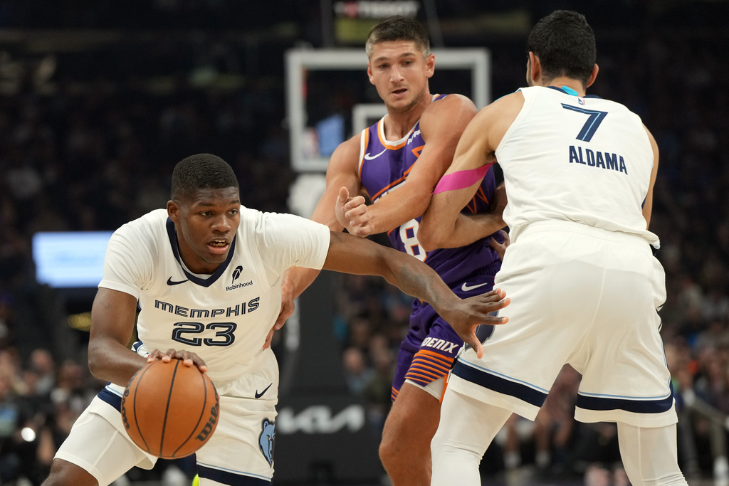 Memphis Grizzlies forward Cedric Coward (23) drives around Phoenix Suns guard Grayson Allen (8) and Santi Aldama during the first half of an NBA basketball game, Wednesday, Oct. 29, 2025, in Phoenix. (AP Photo/Rick Scuteri)