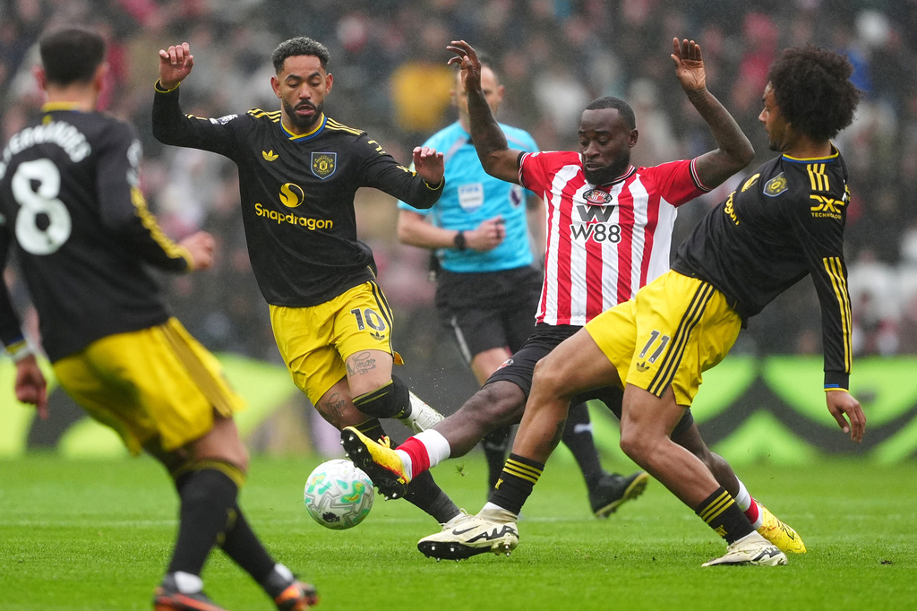 Sunderland's Lutsharel Geertruida is challenged by Manchester United's Matheus Cunha and Joshua Zirkzee, right, during the English Premier League soccer match between Sunderland and Manchester United in Sunderland, England, Saturday May 9, 2026. (Owen Humphreys/PA via AP)