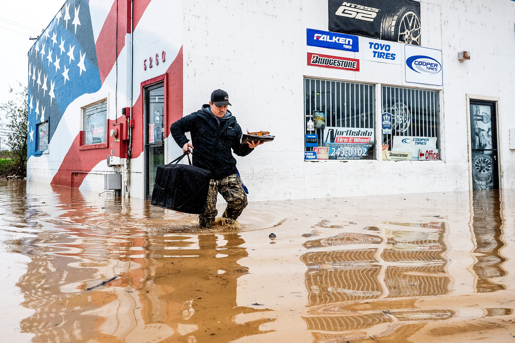 Dekoda Cruz walks through flood water while helping a friend who's tire shop flooded during heavy rains on Monday, Dec. 22, 2025, in Redding, Calif. (AP Photo/Noah Berger)