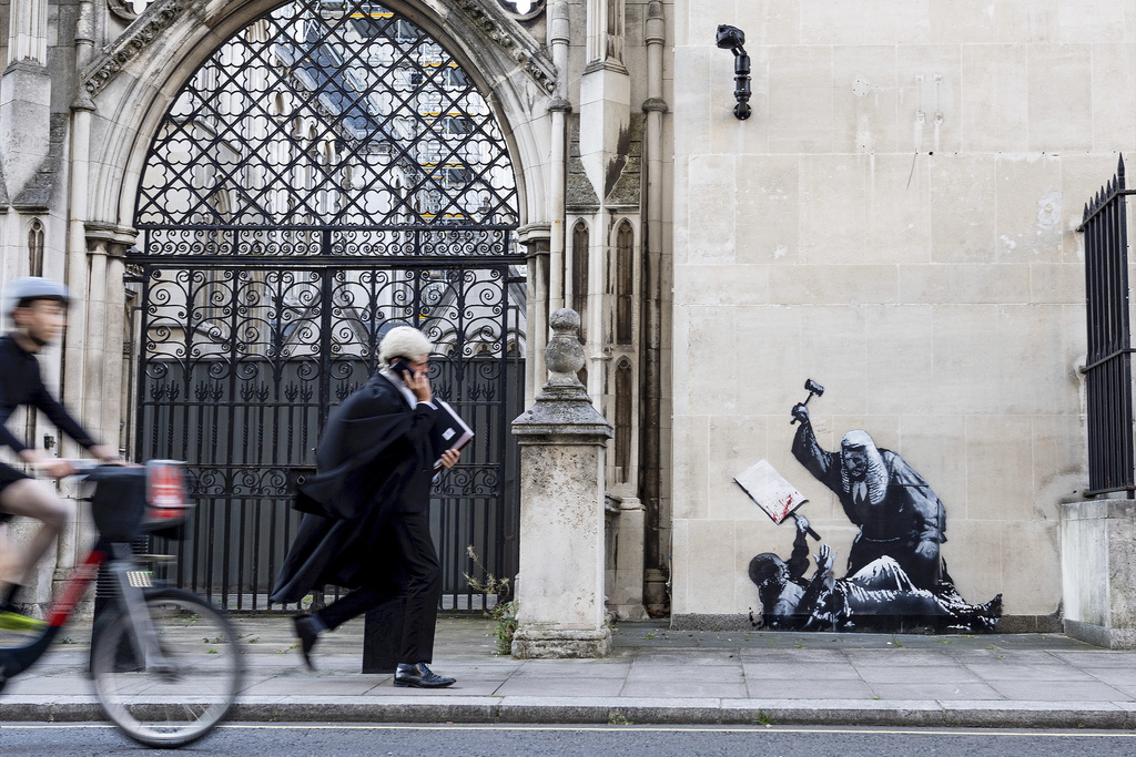 Undated photo released by Banksy of the new artwork by the artist which portrays a judge beating a protester with a gavel at the Royal Courts of Justice in London. (Banksy via AP)