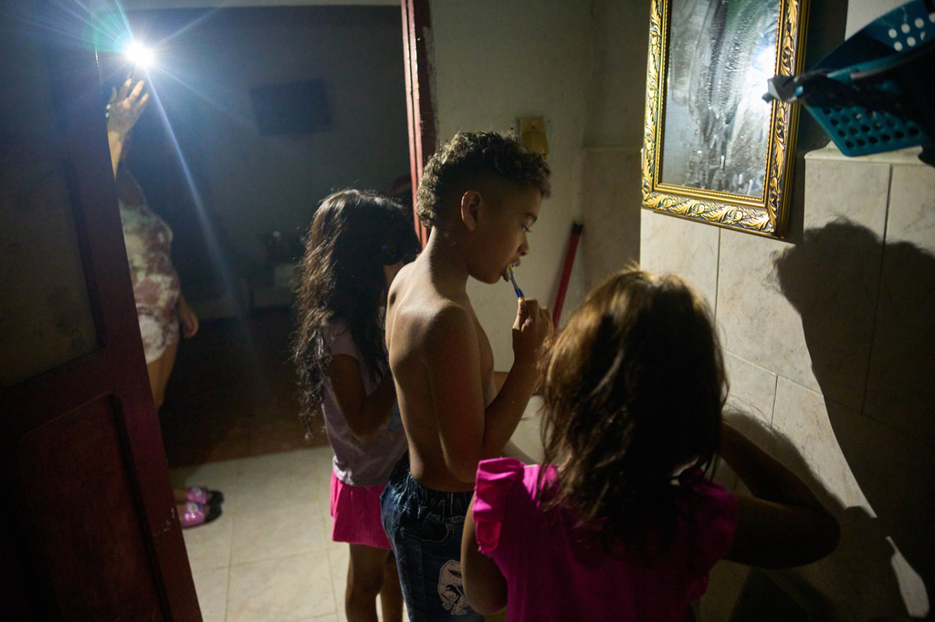 Yurima Izaguirre, left, shines her cell phone flashlight during a blackout as her children brush their teeth and get ready for their first day back to school in Minas, Cuba's Havana province, Tuesday, Sept. 1, 2026. (AP Photo/Ramon Espinosa)