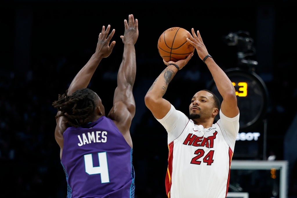Miami Heat guard Norman Powell (24) shoots against Charlotte Hornets guard Sion James during the first half of an NBA basketball game, Tuesday, March 17, 2026, in Charlotte, N.C. (AP Photo/Nell Redmond)