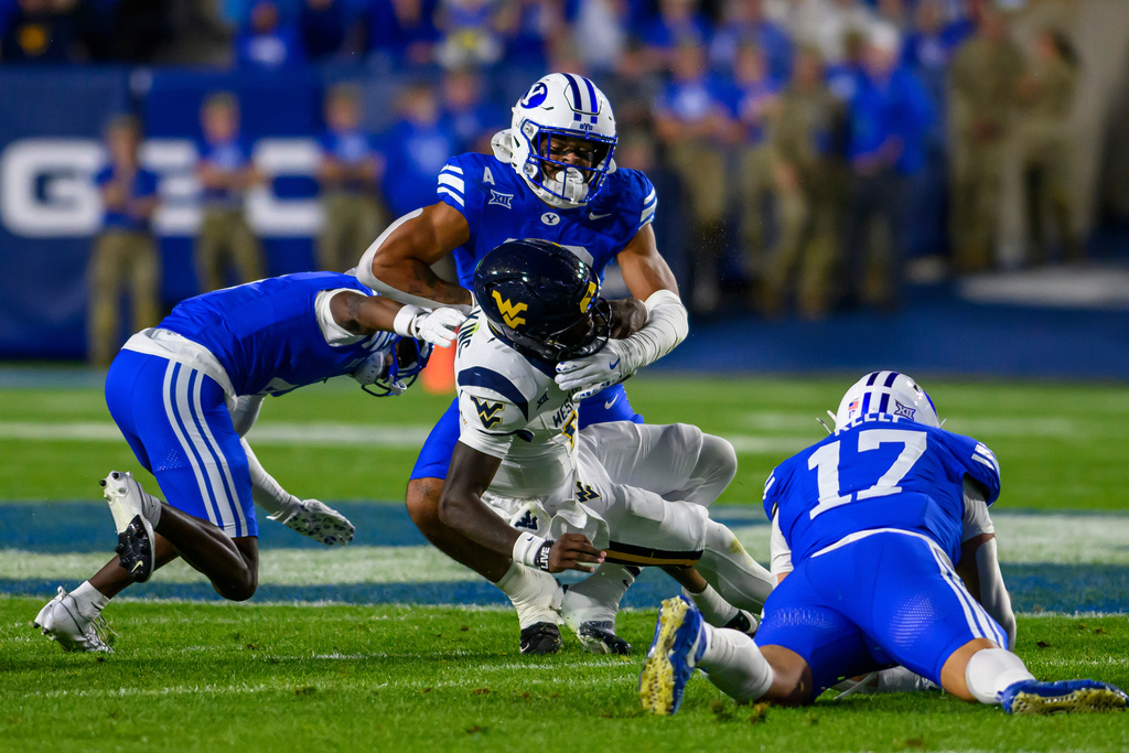 BYU linebacker Isaiah Glasker (16) tackles West Virginia quarterback Khalil Wilkins (14) for a loss of yardage during the first half of an NCAA college football game, Friday, Oct. 3, 2025, in Provo, Utah. (AP Photo/Tyler Tate)