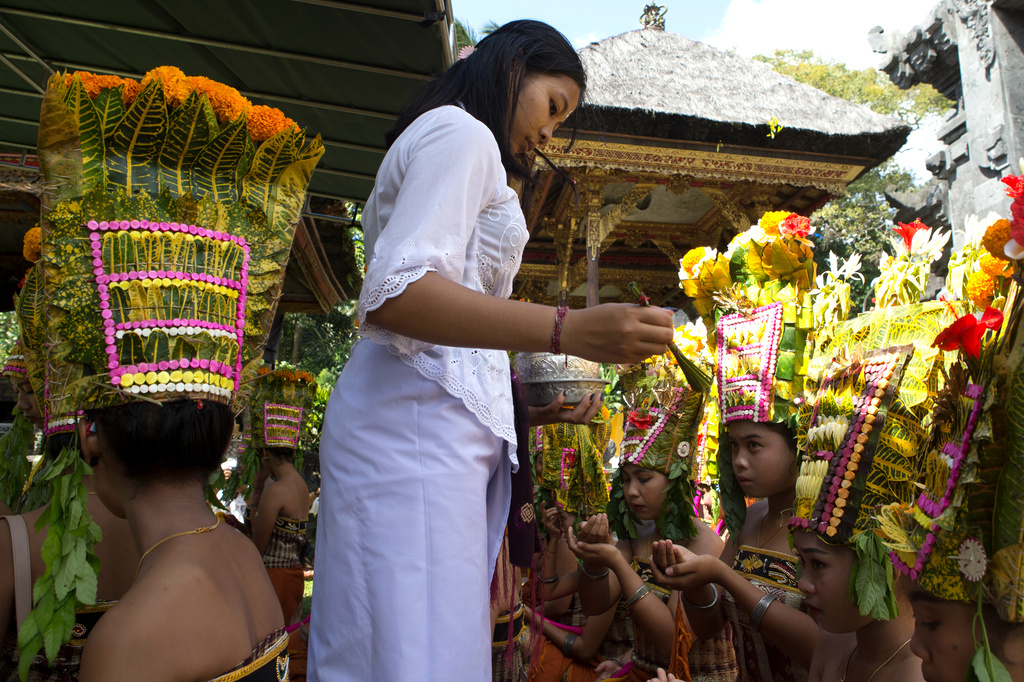 A religious volunteer, locally called "ngayah" gives blessing to dancers before performing the sacred Rejang dance during Kuningan holiday, which marks the end of the 10-day Galungan festival celebrating the victory of good over evil, in Karangasem, Bali, Indonesia, Saturday, June 27, 2026. (AP Photo/Firdia Lisnawati)