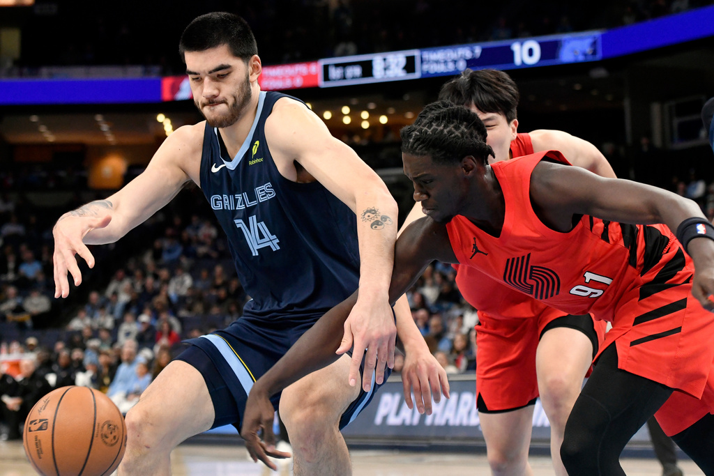 Memphis Grizzlies center Zach Edey (14) and Portland Trail Blazers guard Sidy Cissoko (91) reach for the ball in the first half of an NBA basketball game Sunday, Dec. 7, 2025, in Memphis, Tenn. (AP Photo/Brandon Dill)