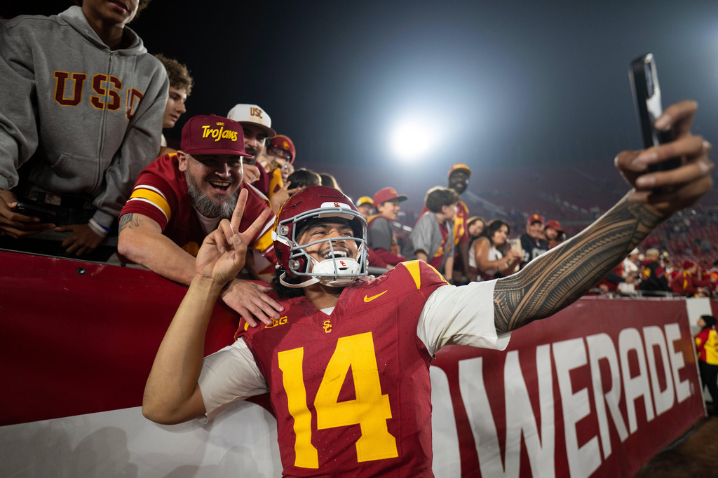FILE - Southern California quarterback Jayden Maiava (14) takes a selfie with fans after an NCAA college football game against UCLA, Nov. 29, 2025, in Los Angeles. (AP Photo/Kyusung Gong, File)