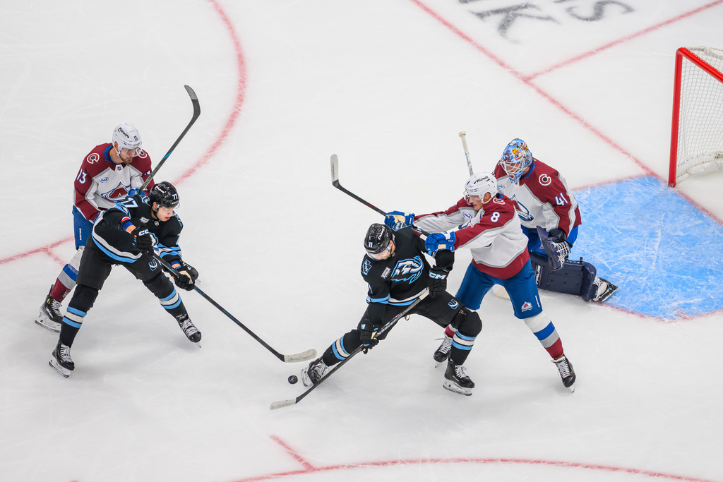 Utah Mammoth right wing Dylan Guenther (11) and right wing JJ Peterka (77) play the puck towards the goal defended by Colorado Avalanche right wing Valeri Nichushkin (13) and defenseman Cale Makar (8) as goaltender Scott Wedgewood (41) protects the net during the first period of an NHL hockey game Tuesday, Oct. 21, 2025, in Salt Lake City. (AP Photo/Tyler Tate)