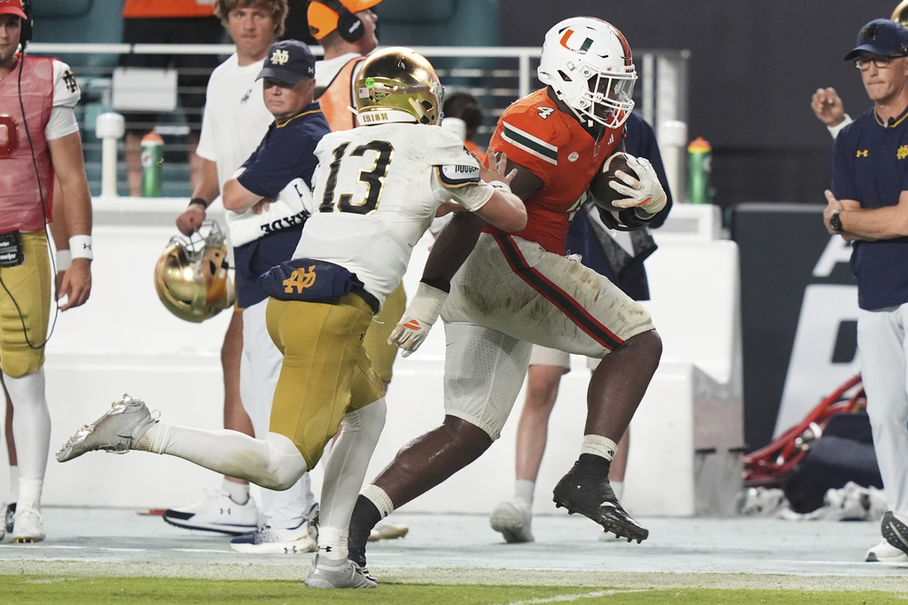 Miami defensive lineman Rueben Bain Jr., right, runs after intercepting the football thrown by Notre Dame quarterback CJ Carr (13) during the second half of an NCAA college football game, Sunday, Aug. 31, 2025, in Miami Gardens, Fla. (AP Photo/Lynne Sladky)