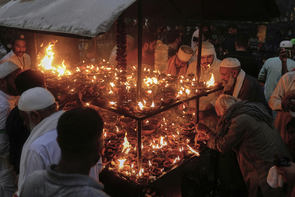 Devotees light clay-lamp during celebrations of the three-day annual festival or 'Urs' of mystic and scholar Hazrat Ali Hajveri, popularly known as Data Ganj Bakhsh at his shrine, in Lahore, Pakistan, Wednesday, Aug. 13, 2025. (AP Photo/K.M. Chaudary)