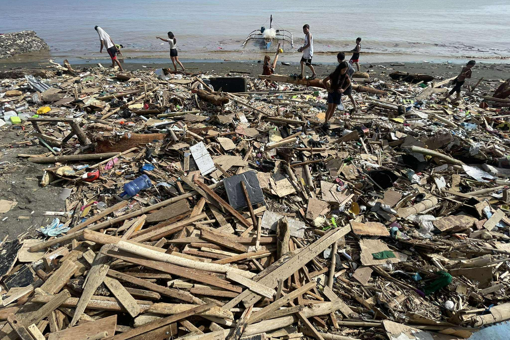 Residents walk along debris along a shoreline after Typhoon Kalmaegi caused devastation in communities at Talisay City, Cebu province, central Philippines, Wednesday, Nov. 5, 2025. (AP Photo/Jacqueline Hernandez)