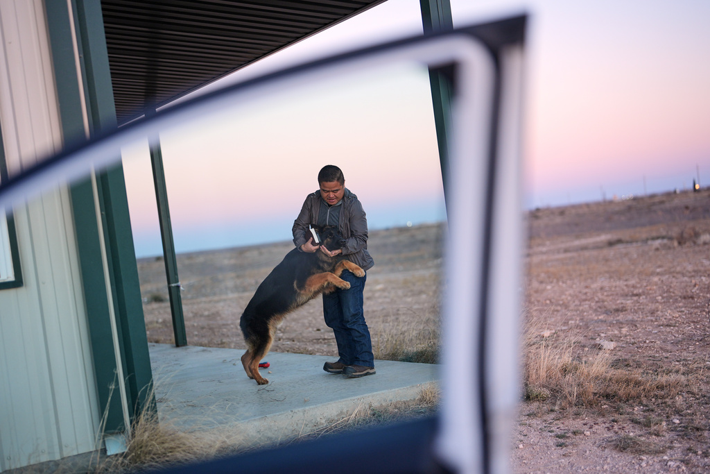 Former Chinese official Li Chuanliang greets his German shepherd, Hardy, as he returns from a trip to town from the Mayflower Church community in Midland, Texas, Jan. 18, 2025. (AP Photo/Rebecca Blackwell)