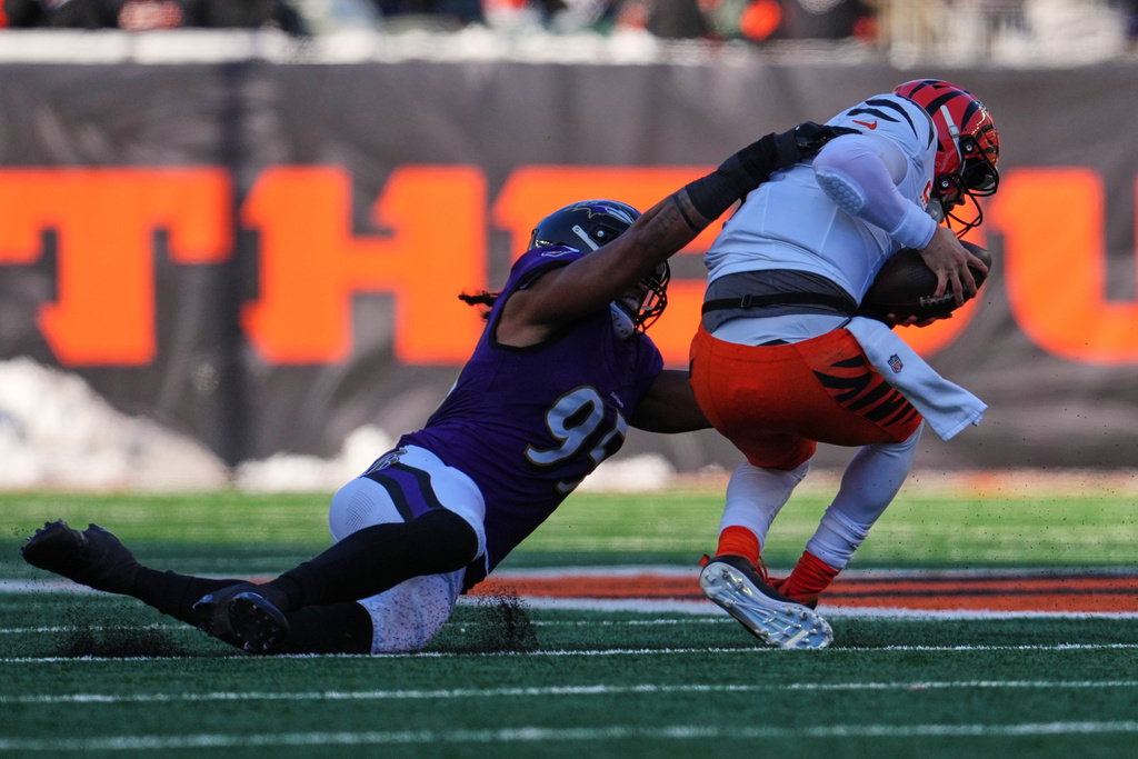 Cincinnati Bengals quarterback Joe Burrow, right, is sacked by Baltimore Ravens linebacker Tavius Robinson (95) during the first half of an NFL football game, Sunday, Dec. 14, 2025, in Cincinnati. (AP Photo/Jeff Dean)