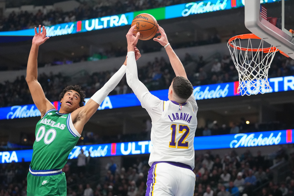Los Angeles Lakers forward Jake LaRavia (12) reaches for a pass as Dallas Mavericks guard Max Christie (00) defends during the first half of an NBA basketball game Saturday, Jan. 24, 2026, in Dallas. (AP Photo/Julio Cortez)