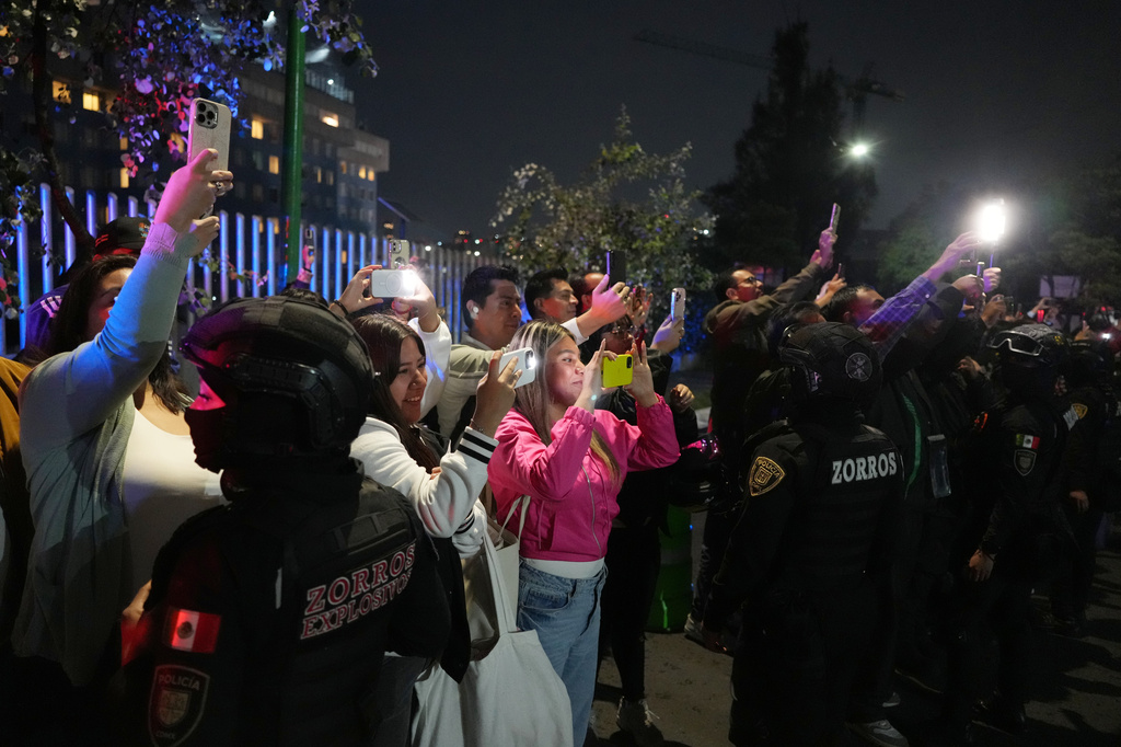 Fans take photos as the England team bus arrives at the hotel where they will stay in Mexico City ahead of its World Cup round of 16 soccer match against Mexico, Friday, July 3, 2026. (AP Photo/Eduardo Verdugo)