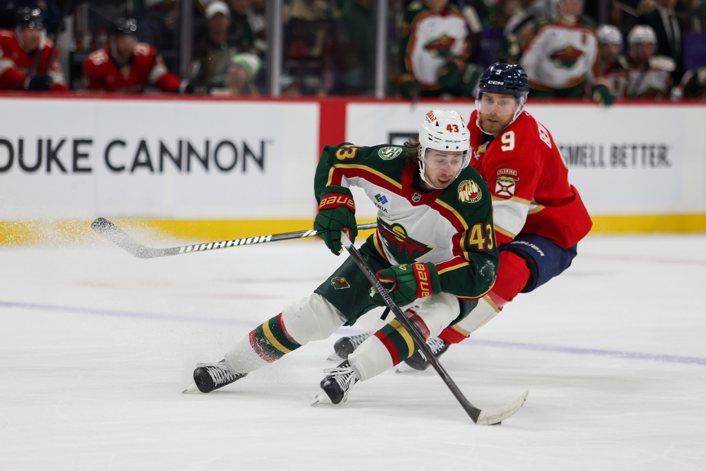 Minnesota Wild's Quinn Hughes (43) controls the puck with Florida Panthers' Sam Bennett (9) right behind him during the second period of an NHL hockey game, Saturday, Jan. 24, 2026, in St. Paul, Minn. (AP Photo/Lily Dozier)