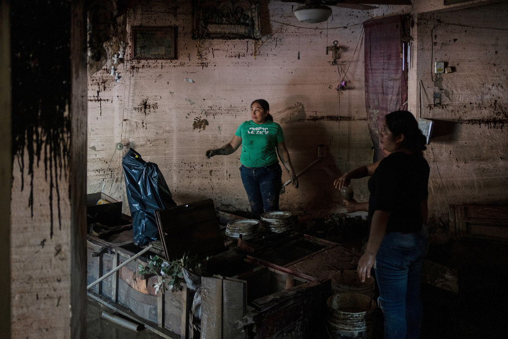 People clean the Ramirez family's flooded house in Poza Rica, Veracruz state, Mexico, Monday, Oct. 13, 2025, after torrential rains. (AP Photo/Felix Marquez)