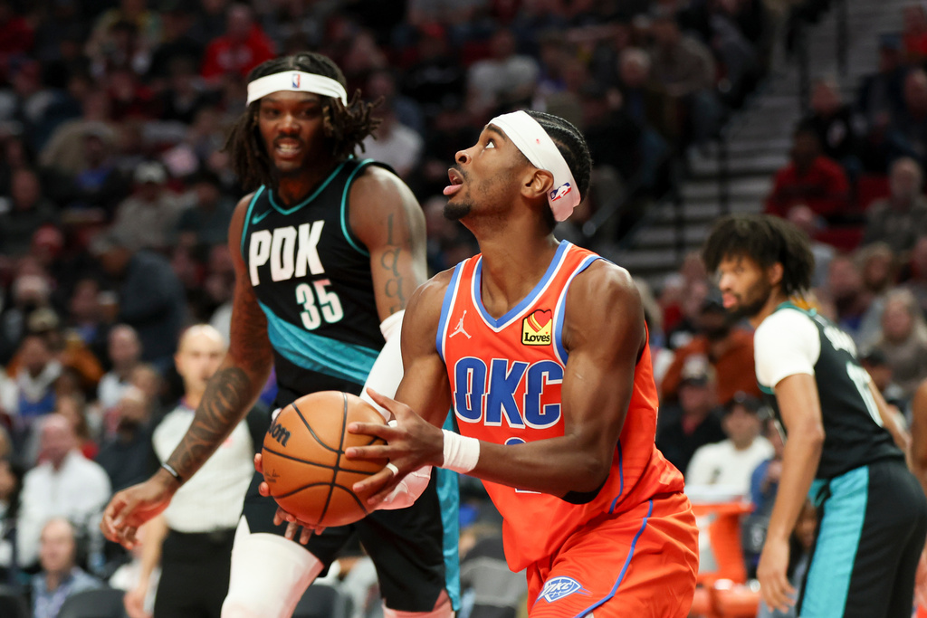 Oklahoma City Thunder guard Shai Gilgeous-Alexander, right, looks to the basket ahead of Portland Trail Blazers center Robert Williams III (35) during the second half of an NBA basketball game, Sunday, Nov. 30, 2025, in Portland, Ore. (AP Photo/Amanda Loman)